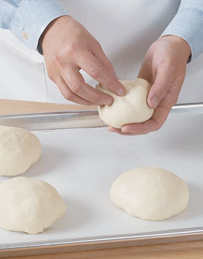 After 2 hours, divide dough into four balls. Pinch bottoms to keep air out and let dough rise 1 hour more.