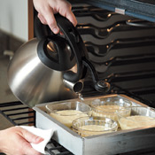 Pour hot water into the pan in the space around the ramekins until water level is halfway up the sides.