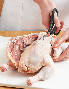So the chicken lays flat in the skillet, cut along both sides of the backbone with scissors to remove it.