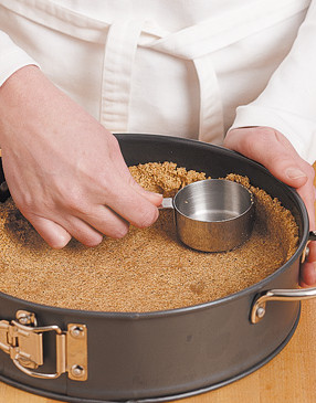 A small measuring cup is an ideal tool to press the crumbs into the edges and up the sides of the pan.