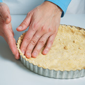 Press the dough evenly on the bottom and up the sides of the pan. Prick the dough with a fork, then bake. 