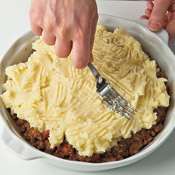 Using a fork, spread the potato topping evenly over the meat mixture. The fork tines add interesting texture.
