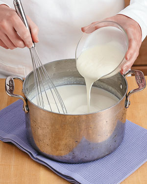 Adding yogurt starter to cooled milk for homemade yogurt