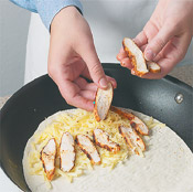 Put down layers of cheese, chicken, and more cheese on side of the tortilla, then fold over and saute. 