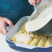 Arrange the rolled manicotti in the prepared baking dish and drizzle the remaining béchamel over the top.