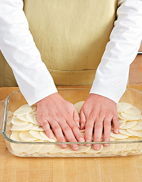 To compact the potatoes and make them lie flat in the pan, press down on each layer of potatoes.