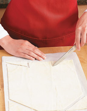 Roll pastry, transfer to parchment, then cut off top corners. Notch bottom to create end flaps.