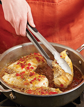 As the chicken simmers in the sauce, flip it periodically to evenly coat it with spicy-sweet flavor.