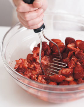 Crush halved strawberries with a potato masher until broken but still chunky. Transfer crushed berries and liquid to pot.