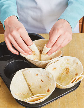 Pleat the tortillas so they fit snugly into the muffin tin wells and so they’re the right size for the filling.