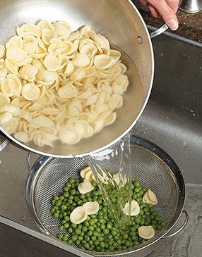 Drain the cooked pasta over the peas. The hot pasta water will cook them slightly, taking off the raw edge.