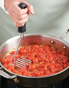 Crush tomatoes with a masher to release juices into the sauce, leaving some whole for texture.