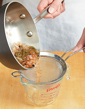 Strain vinegar and wine reduction through a mesh sieve to catch the solids, then discard them.
