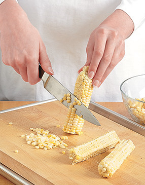 To remove kernels, run a knife down sides of cobs on a cutting board on a baking sheet to catch kernels.