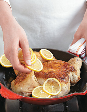 Top the seared chicken with lemons, then roast in the oven. The lemons add flavor to the chicken as they caramelize.