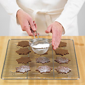To decorate baked cookies, scoop some powdered sugar into a fine-meshed sieve and tap repeatedly.