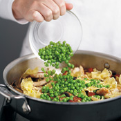 Return cooked chicken to the pan, then add farfalle and frozen peas before stirring in the alfredo sauce. 