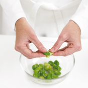 After blanching and shocking favas, peel off their outer shell, which is hard to digest, to reveal bright green beans.