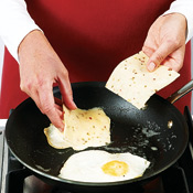 Cook eggs, pierce yolks, then flip eggs over. Top with cheese, and cover skillet to melt the cheese.

