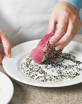 Press seasoned tuna steak firmly into black and white sesame seeds to coat fish on only one side.