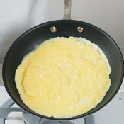 Tilt skillet to roll excess egg mixture around to the edges of the omelet.