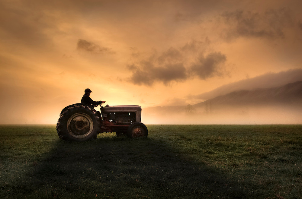 Farmer on tractor at dusk.