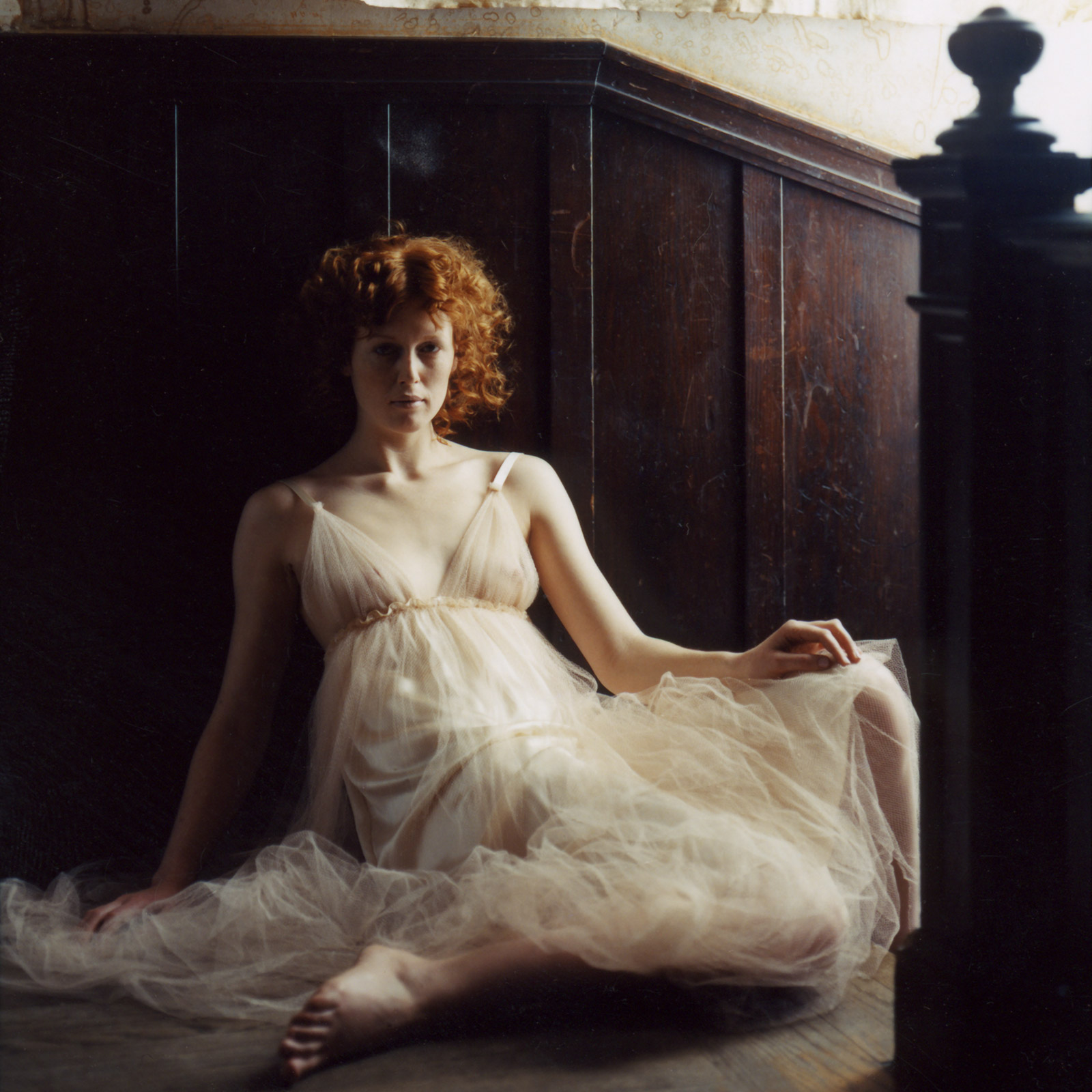 woman with red hair sitting at top of staircase wearing long white dress