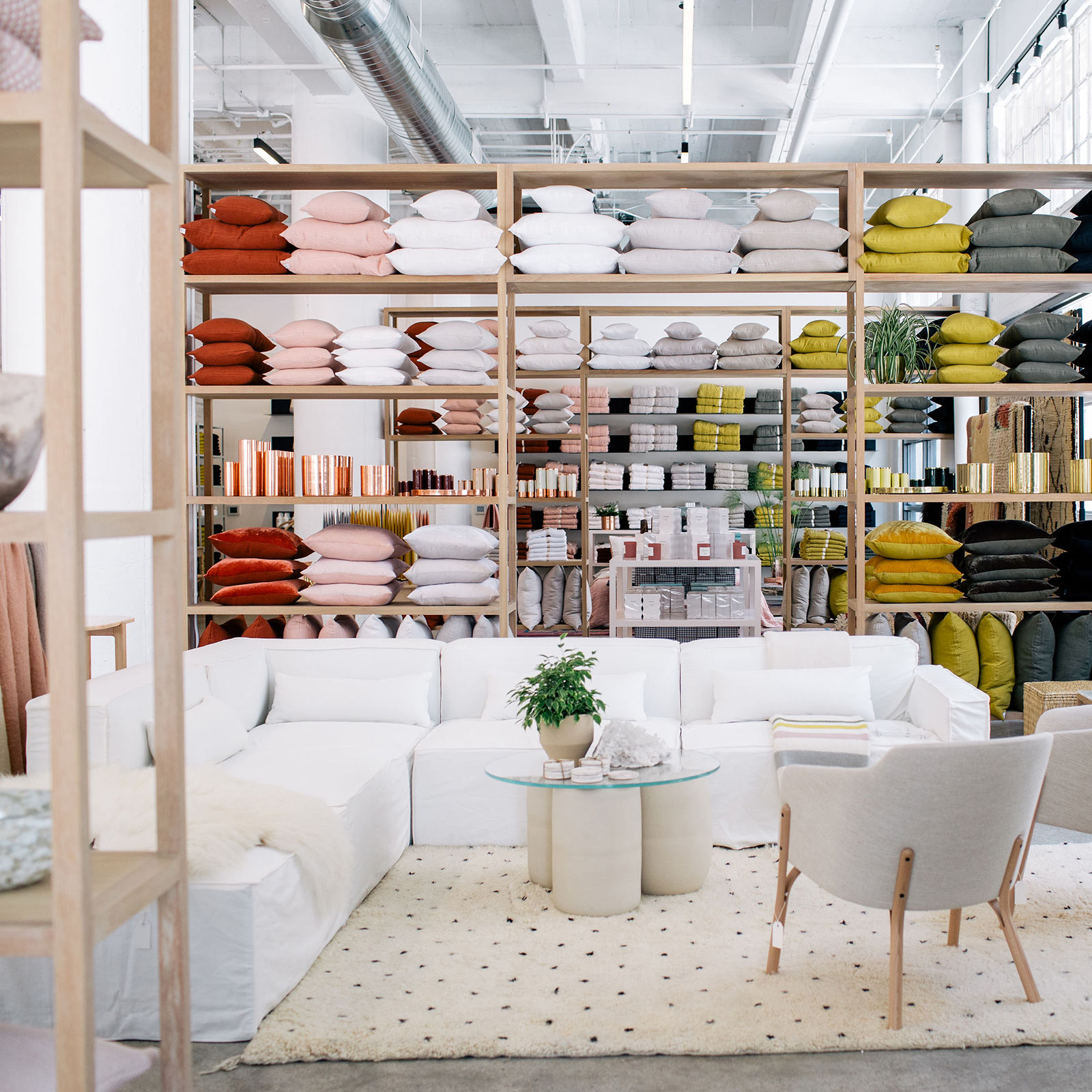 luxury bedding inside store with white chairs and white couch and white rug