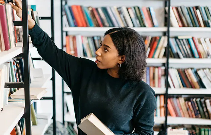 Woman putting a book on a bookstore shelf.