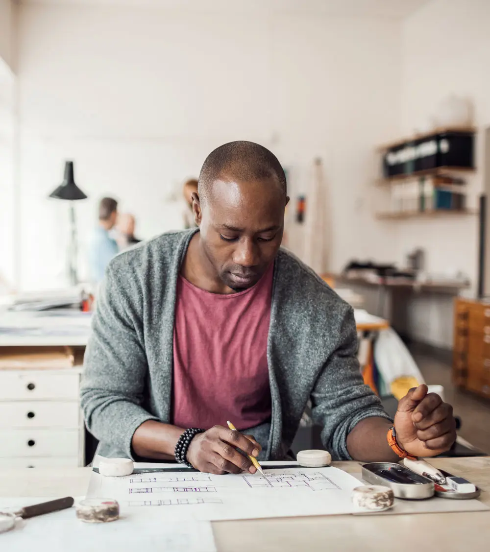 Man at desk editing a layout plan document with a pen