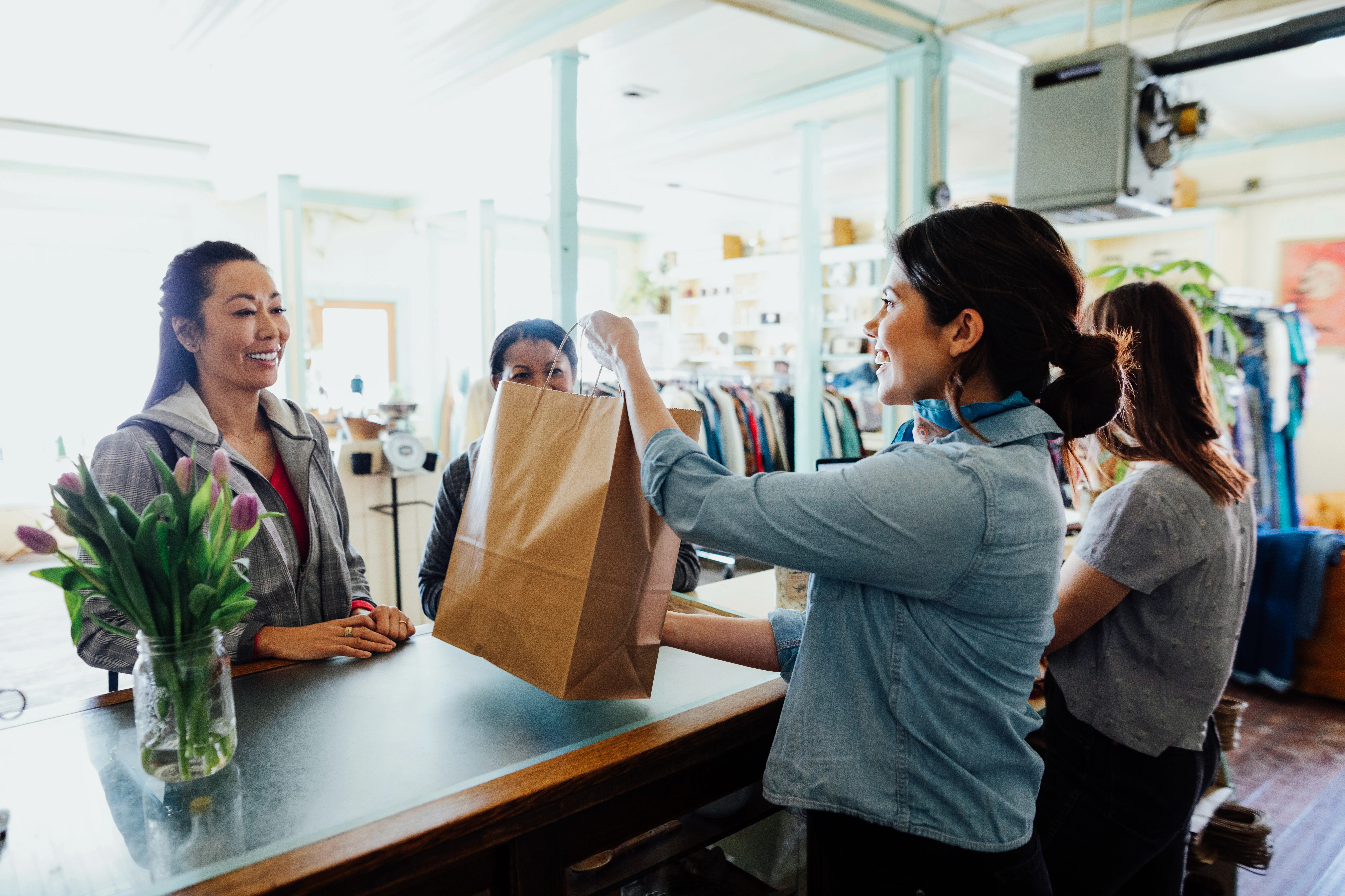 Woman getting delivery of purchased products from the shopkeeper at the delivery counter of a dress shop