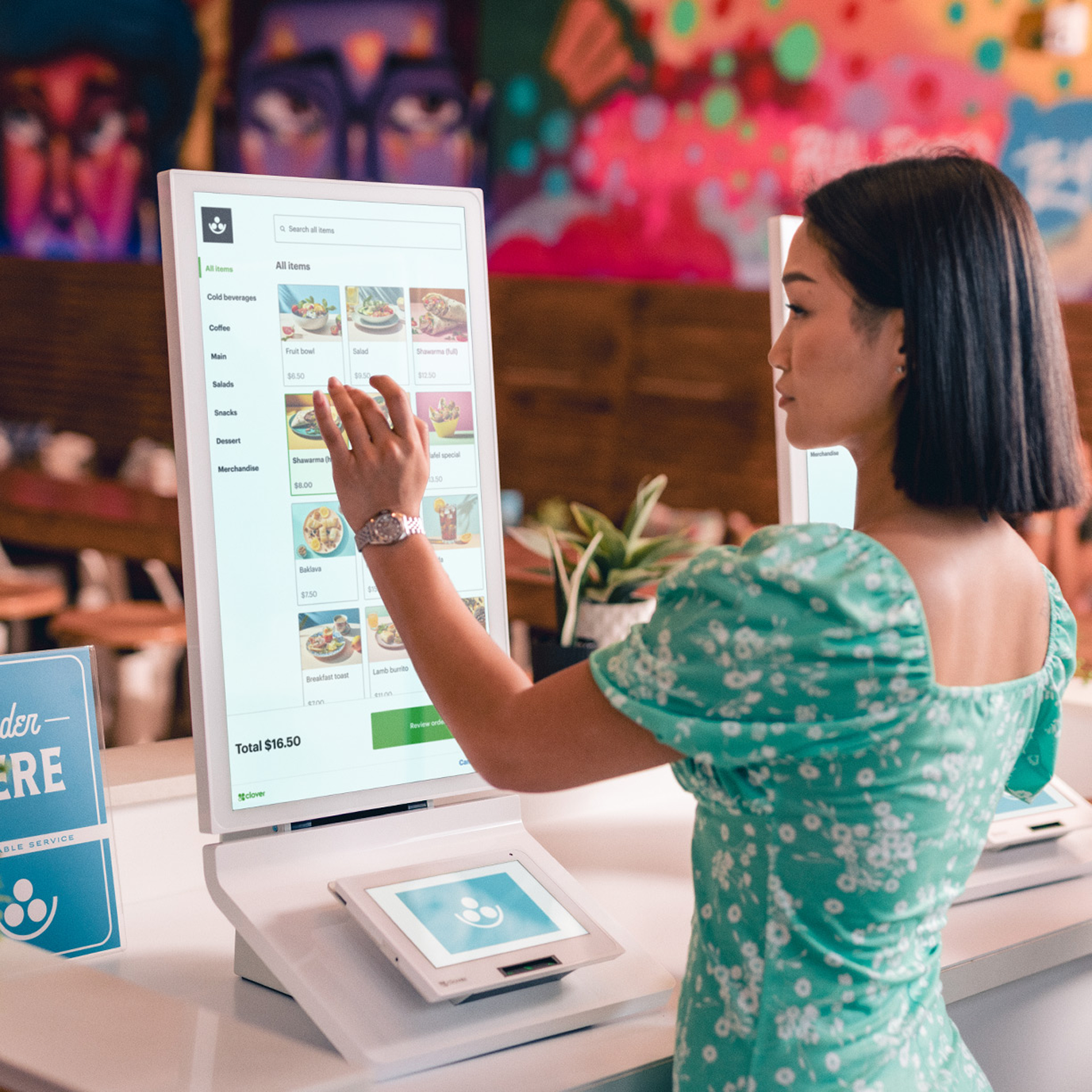A lady is seen placing an order from the menu displayed at the Kiosk device