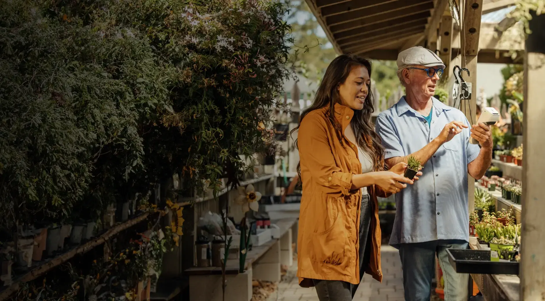 Plant shop employee holding a Clover Flex device assists customer with purchasing a plant.