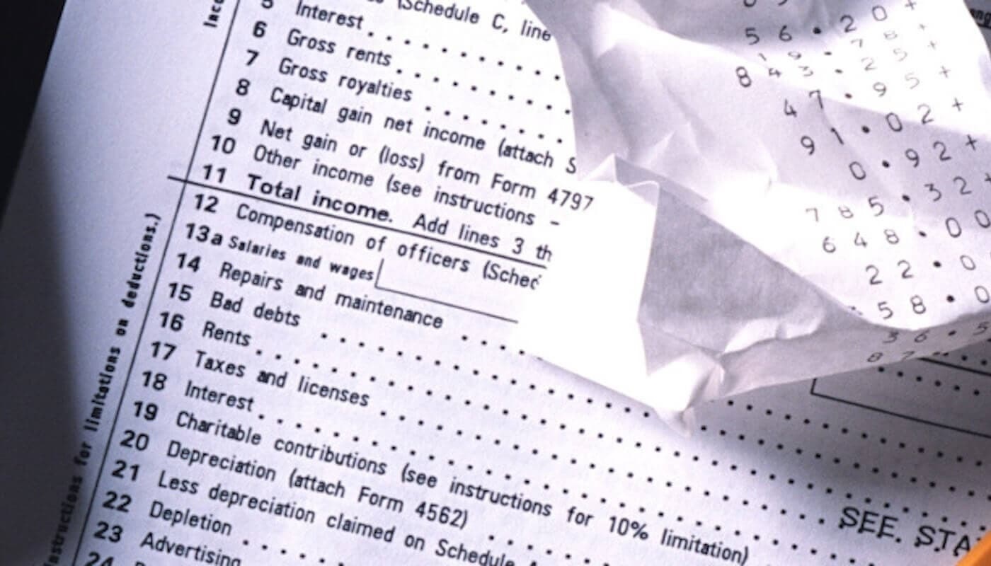 A part of tax return receipt and a crumbled paper with some numbers written on it.