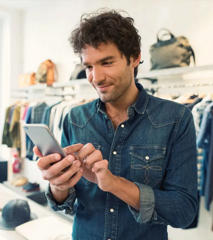 Man at clothing store uses his phone