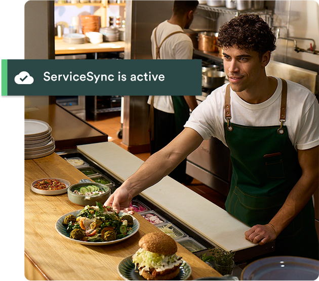 Kitchen worker places plate of food on service counter for pick up.