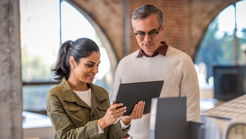 Two professionals looking at a digital twin on a tablet