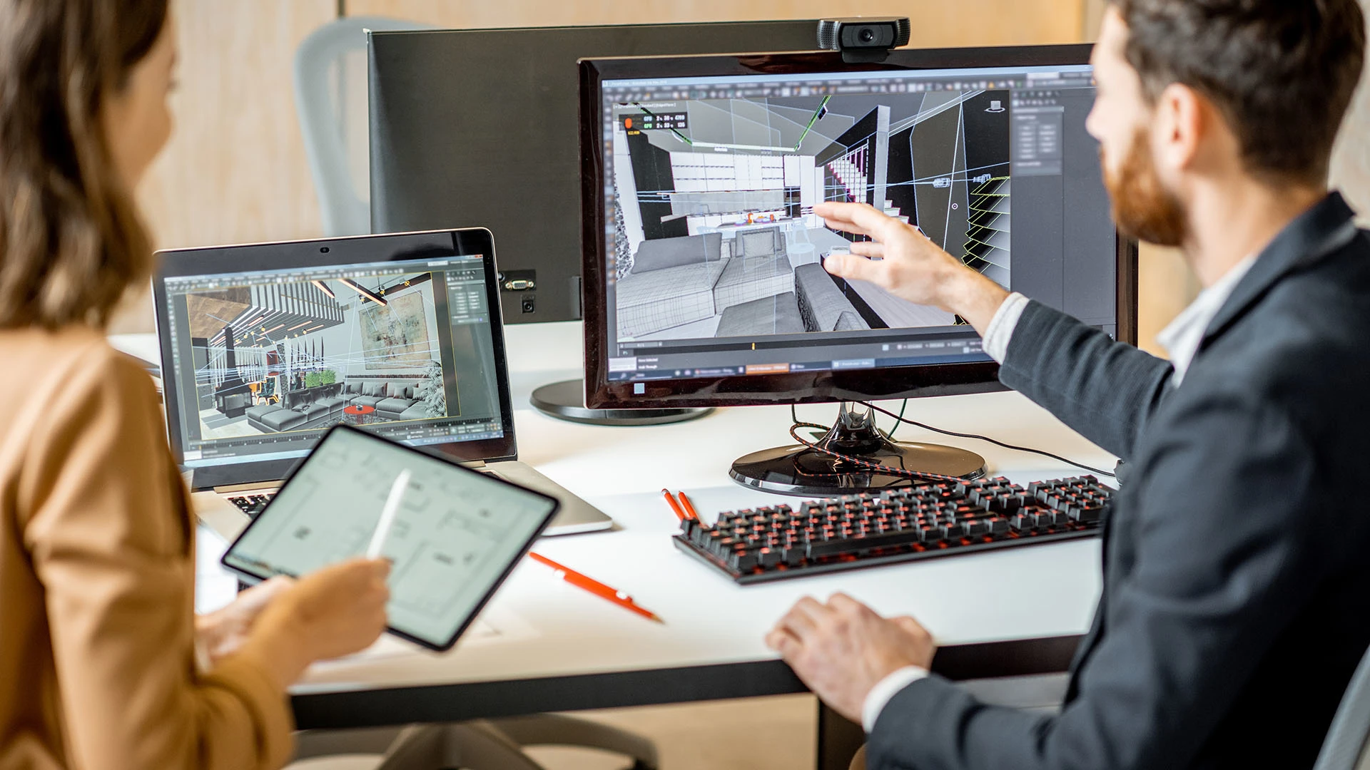 Two office employees work on an interior office design on a computer and digital tablet.