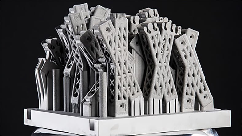 A black and white photo shows gridlike 3D-printed structures on a black background.
