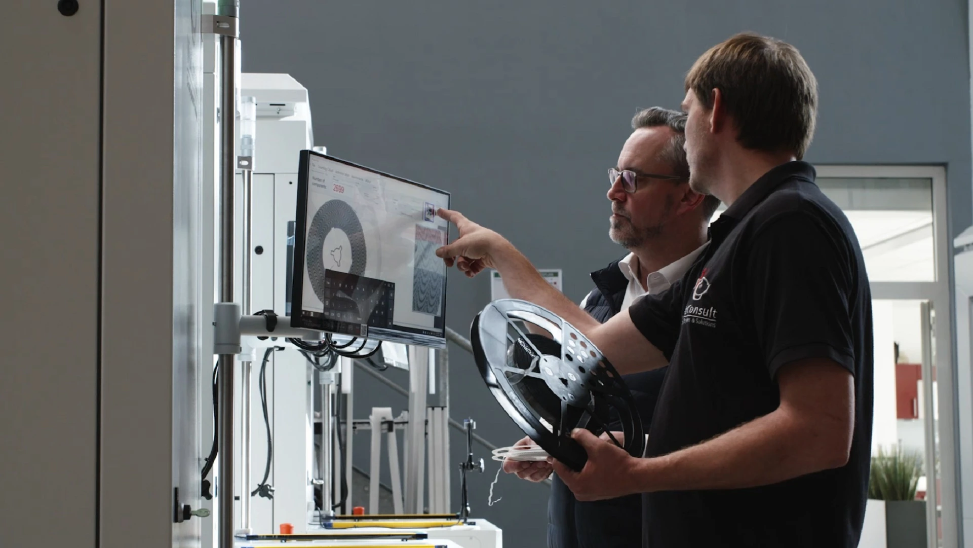 Two men review data on a computer screen for a manufacturing quality-control inspection.