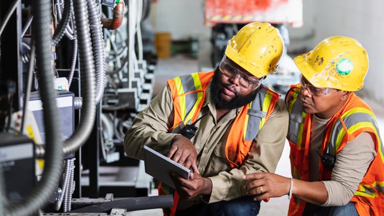 Two workers inspecting industrial refrigeration equipment