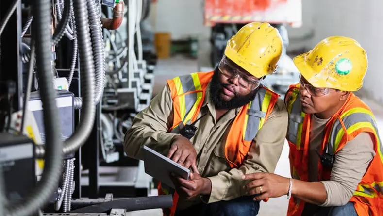 Two workers inspecting industrial refrigeration equipment
