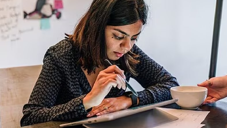 Young female engineering student bent over a tablet