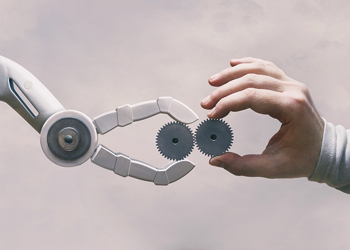 Robot hand and human hand holding interlocking gears manufacturing trends 2022