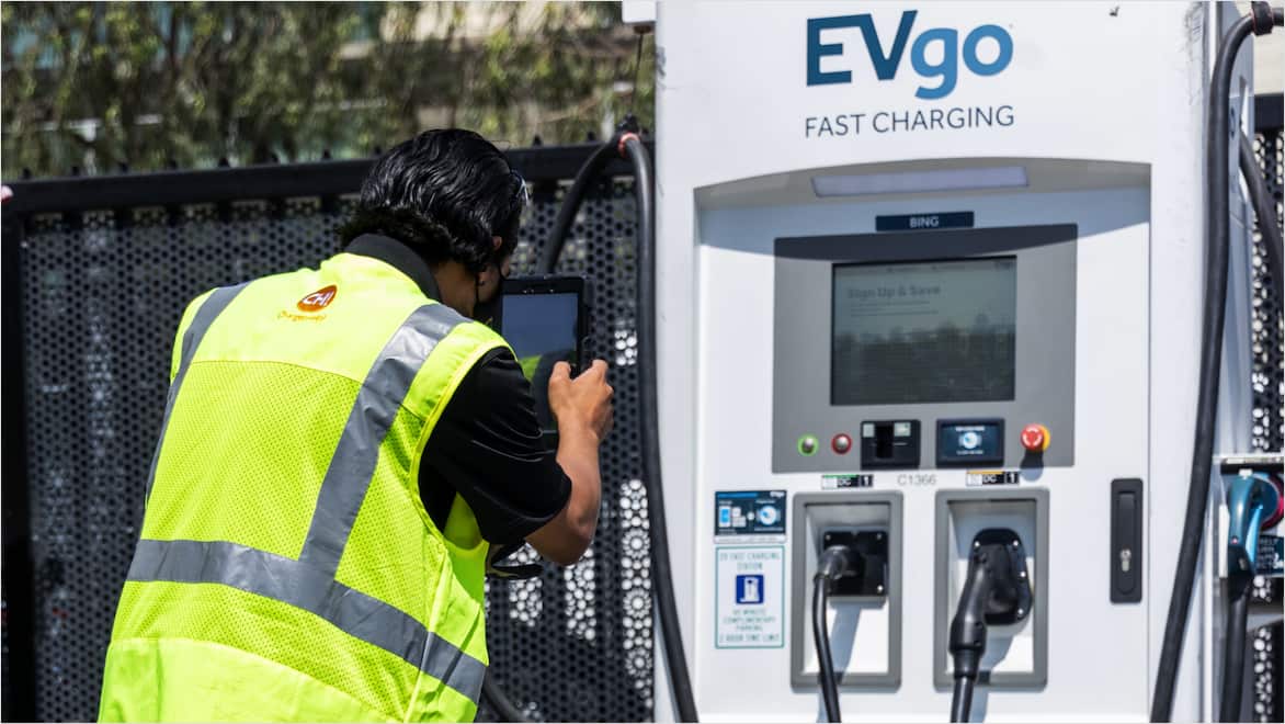 Eye-level view of ChargerHelp! worker standing in front of an EVgo.