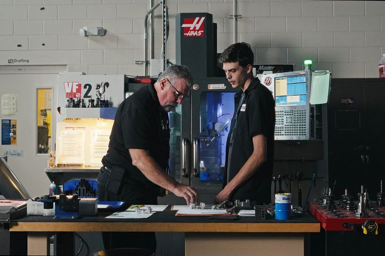 Educator at Suncoast Technical College showing a student a part in a workshop classroom.
