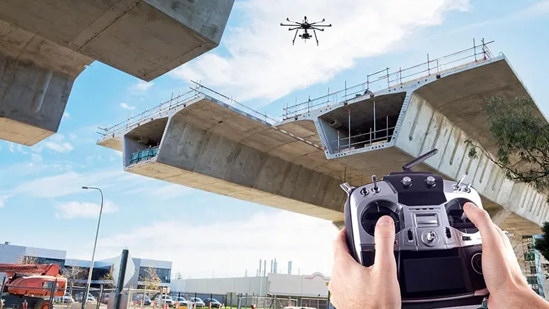 A worker uses a drone to inspect bridge construction.
