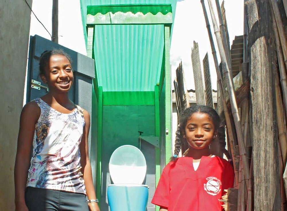 Two Malagasy girls in front of a Loowatt toilet