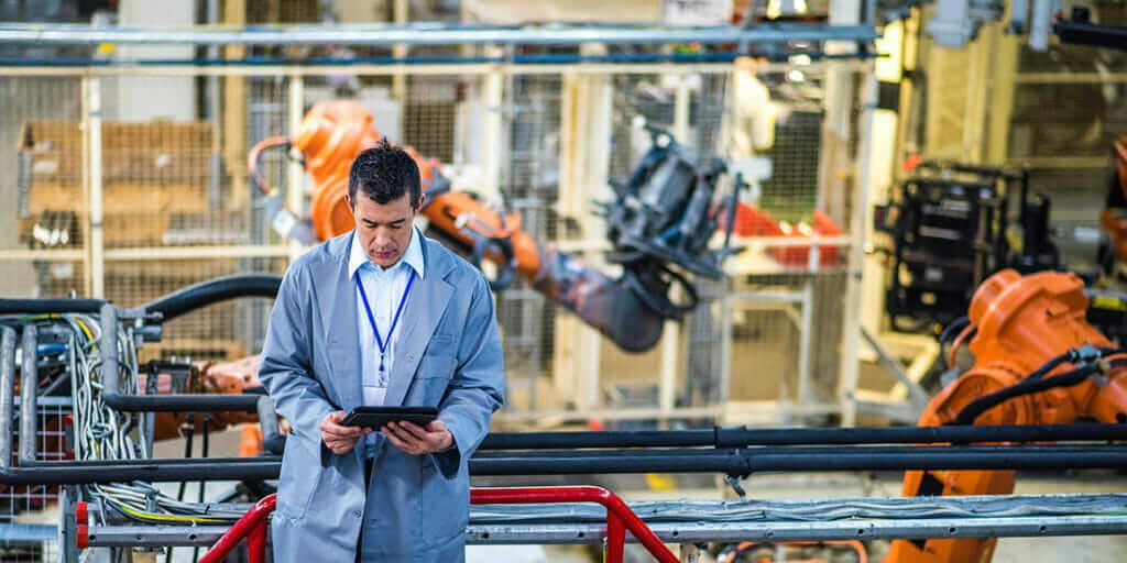 Manager reviewing notes at manufacturing facility using artificial intelligence and autonomous robots