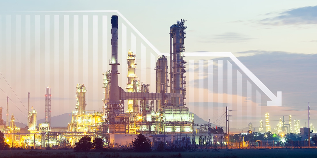 A downward-trending graph is superimposed over a photo of a polluting factory